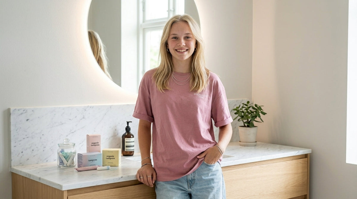 Ung kvinne står på badet ved siden av menstruasjonsprodukter